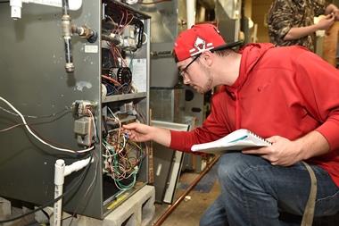 HVAC male student studying the connections in a classroom unit.